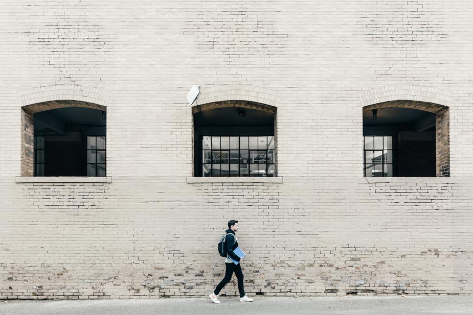 Ein Schüler läuft alleine vor einer Hauswand.
